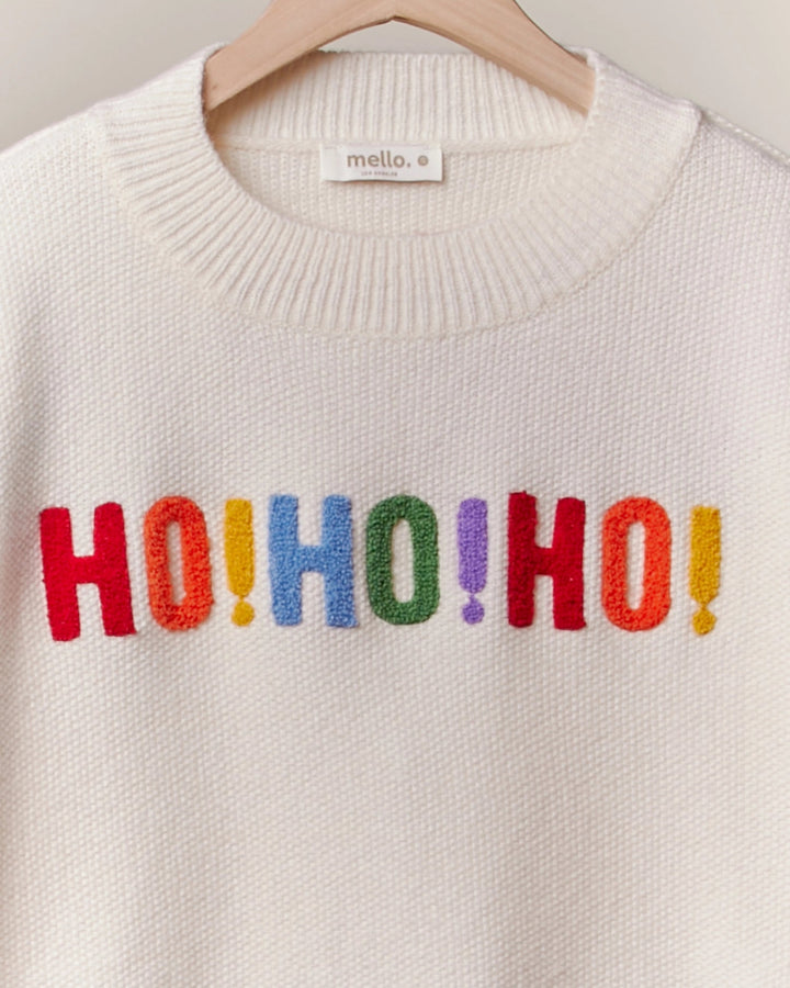 White sweater with colorful 'HO! HO! HO!' text on a hanger.